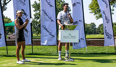 A host at a podium addresses attendees on a golf course
