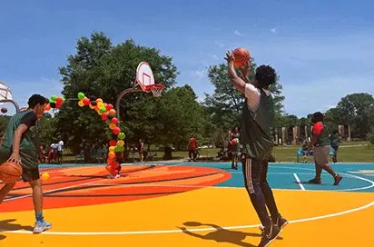 A young person takes the sure shot on an outdoor basketball court