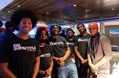 A group of young people wearing black t-shirts that read, "Be Impactful"