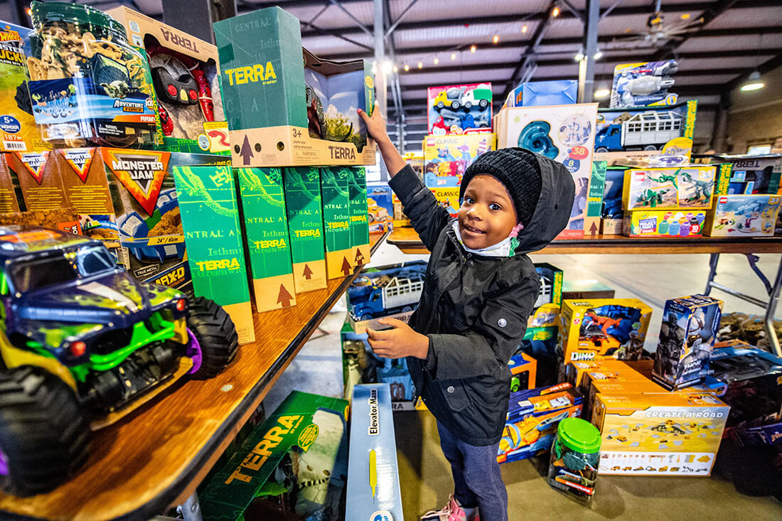 A young child reaches for a toy on a shelf