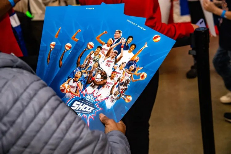A fan holding several Detroit Shock team posters