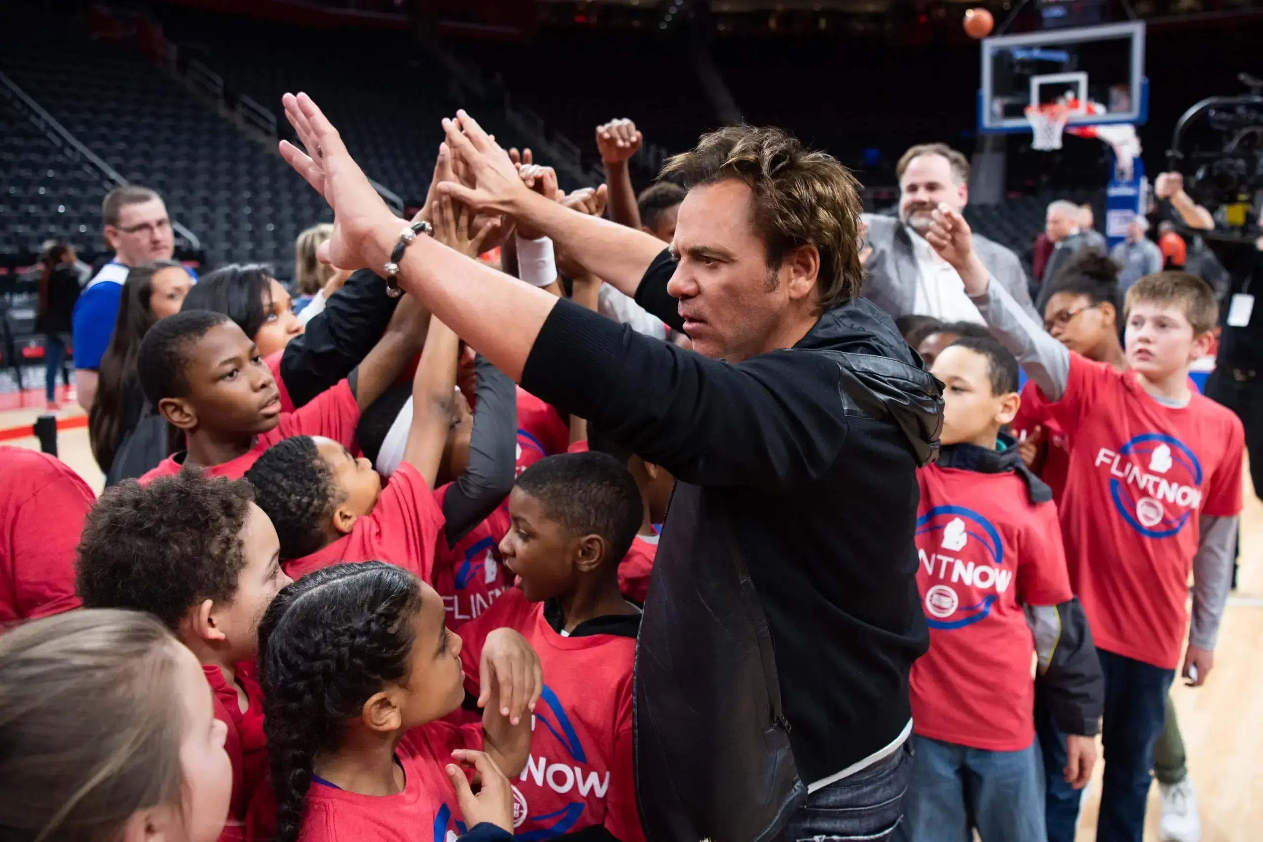 Tom Gores gives high-fives to a crowd of young kids