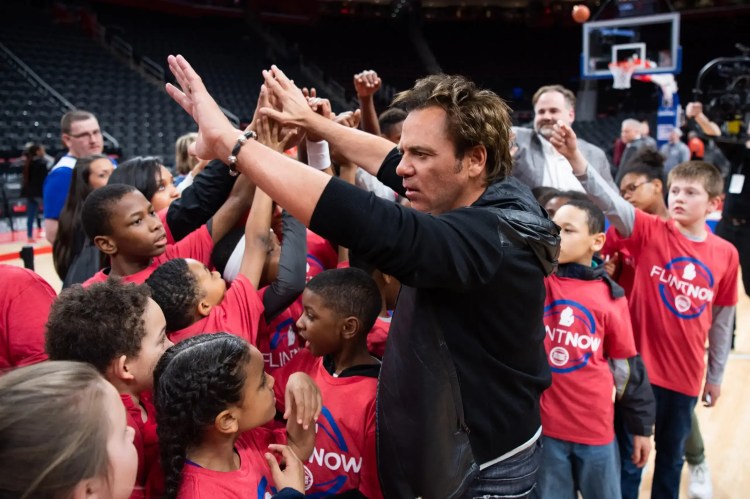 Tom Gores gives high-fives to a crowd of young kids
