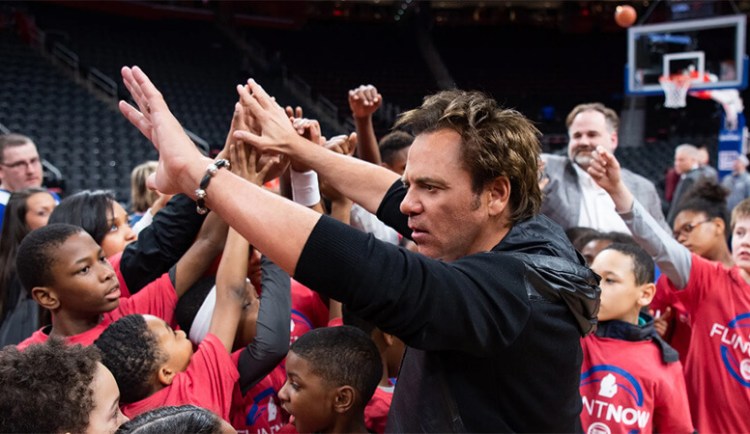 Tom Gores gives high-fives to a crowd of young kids
