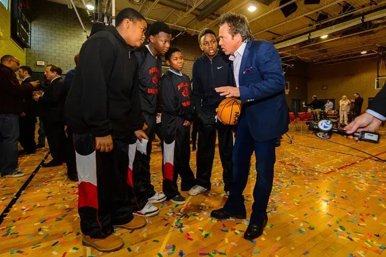 Tom Gores coaches a group of young men on a basketball court