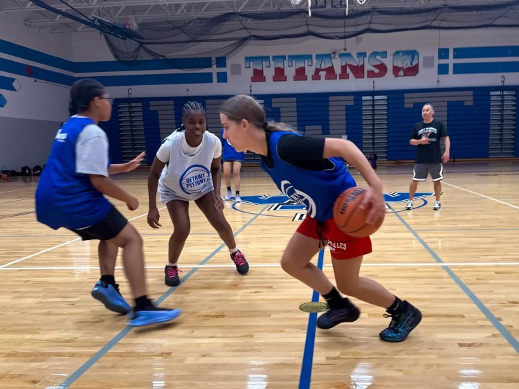 Players compete on a basketball court at a Pistons-themed camp