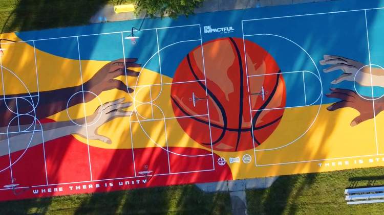 Overhead view of a colorfully painted basketball court with the logo, "Be Impactful"